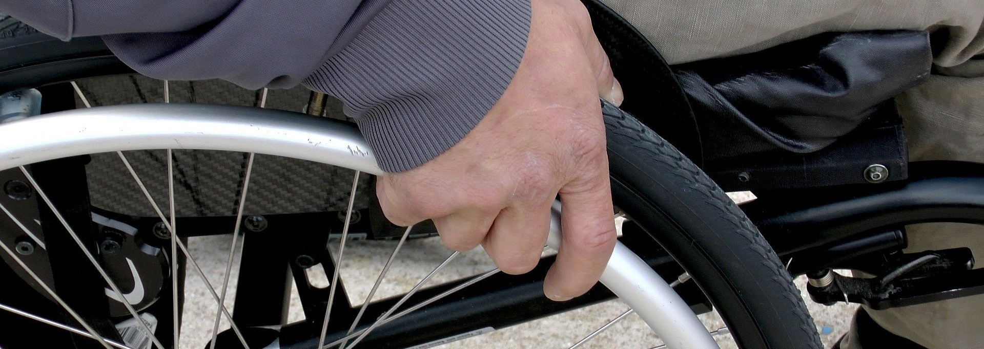 Hand eines Rollstuhlfahrers am Reifen